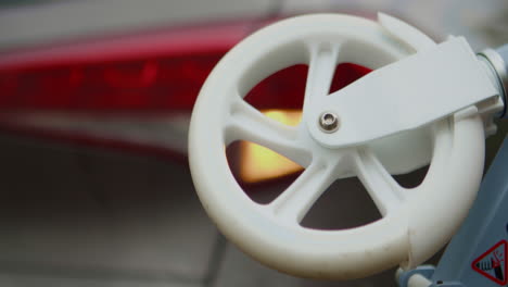 Spinning-scooter-wheel-in-front-of-car-warning-lights