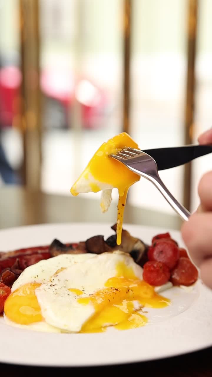 Primo piano di tuorlo d'uovo fritto cremoso tagliato su un piatto da colazione