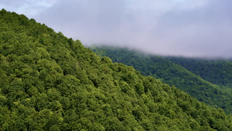 high-altitude drone footage of cloud banks clashing with misty mountain slopes