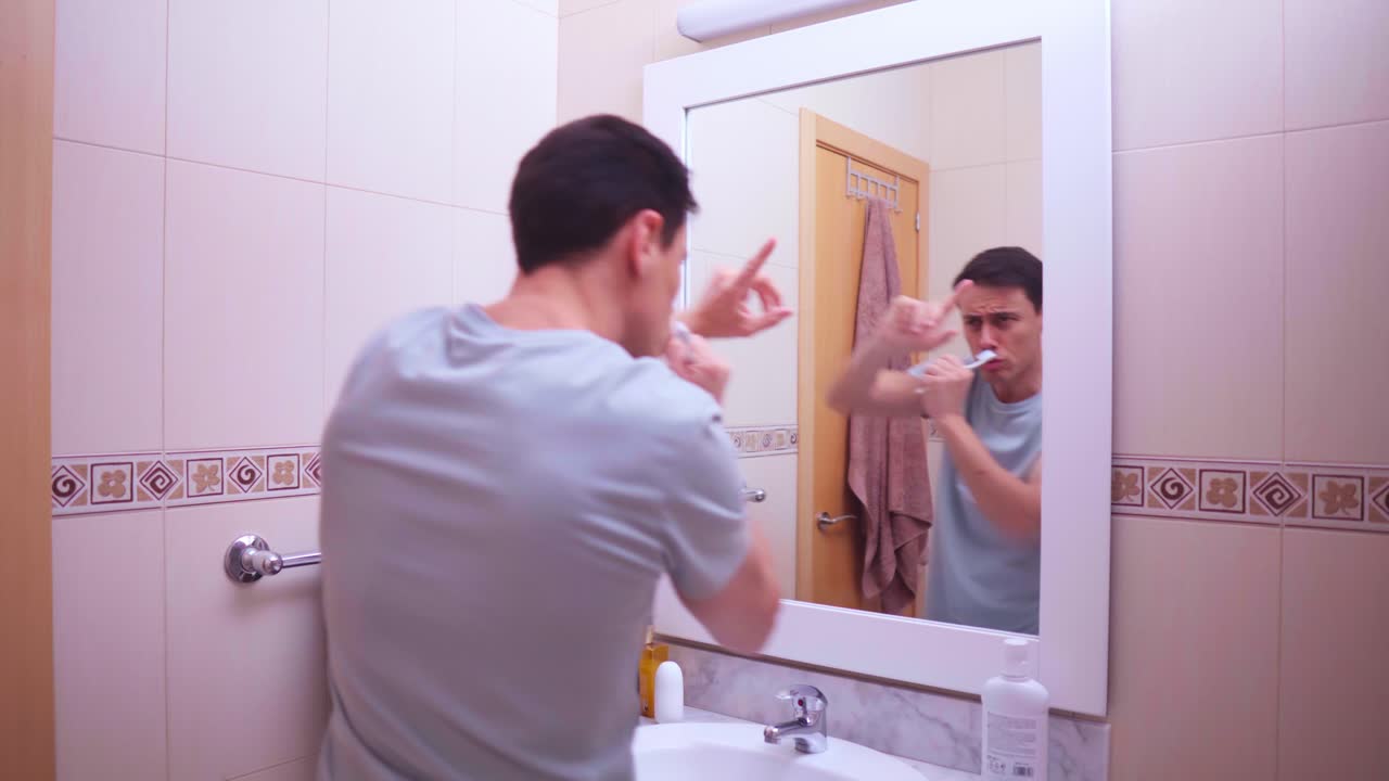 Enthusiastic man singing with toothbrush in bathroom mirror