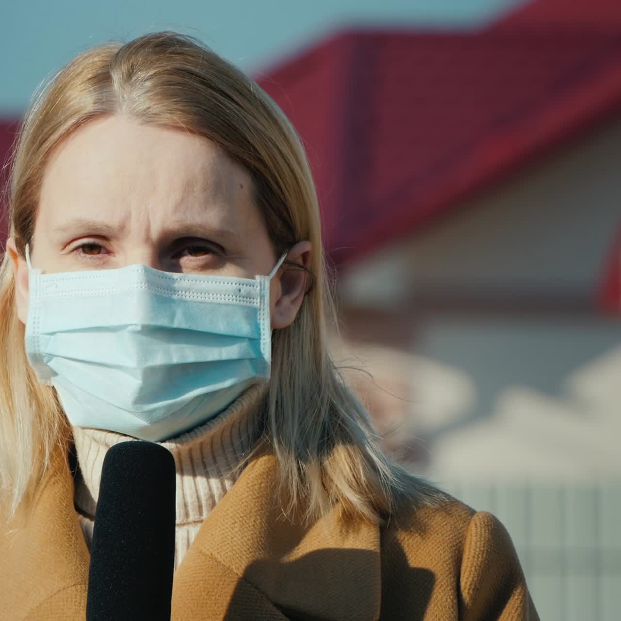 마스크를 쓴 블로거가 야외에서 마이크에 대고 이야기합니다.