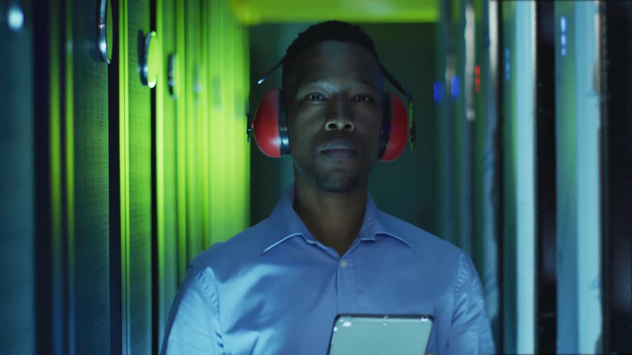 Afroamerikansk mandlig computertekniker, der arbejder med en tablet i et serverrum.