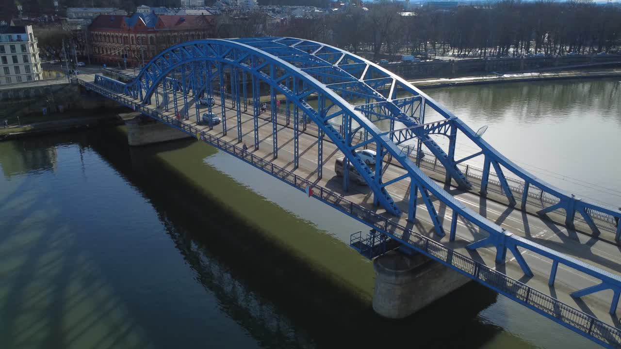 Aerial View of Blue Arched Bridge Over River with Cityscape