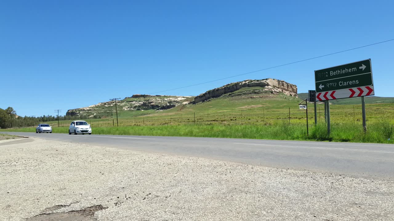 R712 road outside Clarens town in Free-state province South Africa with cars and motorbike traffic traveling past on vacation in Moluti Mountains.