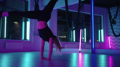 a woman dances in a studio with a neon light performing graceful exercises and movements from stretching and dancing in slow motion