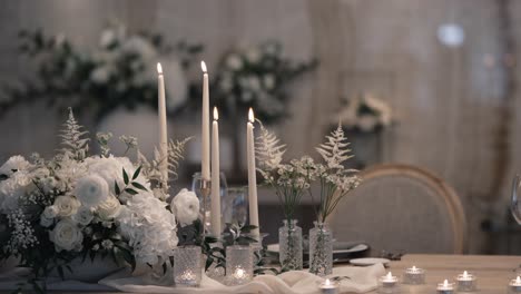 elegante mesa de bodas con pieza central floral blanca y velas cónicas altas