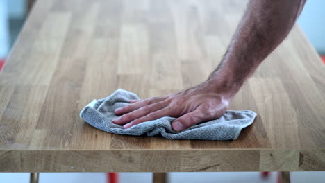 hand wiping wooden surface with cloth in detail domestic chore close-up