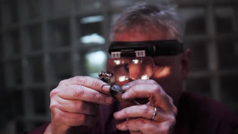 old man inspecting an expensive big gold ring with stones in slow motion