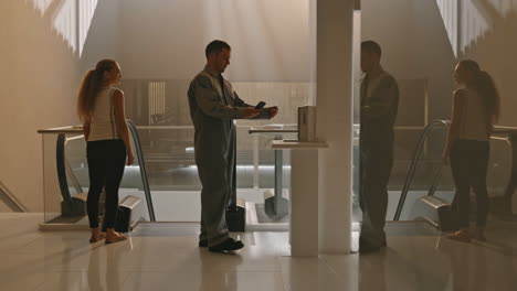 a man interacts with a futuristic digital scanner using a smartphone at an entrance