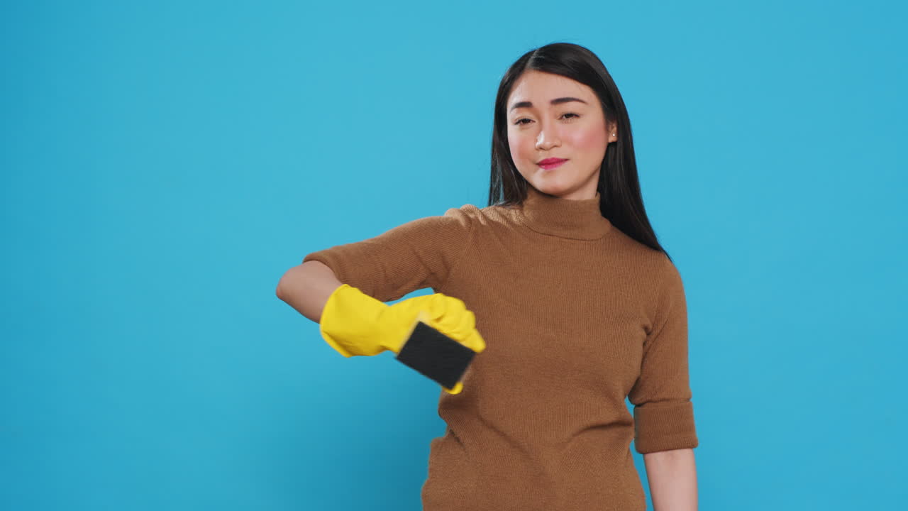 Smiling maid using sponge and professional cleaning detergent while cleaning customer hous
