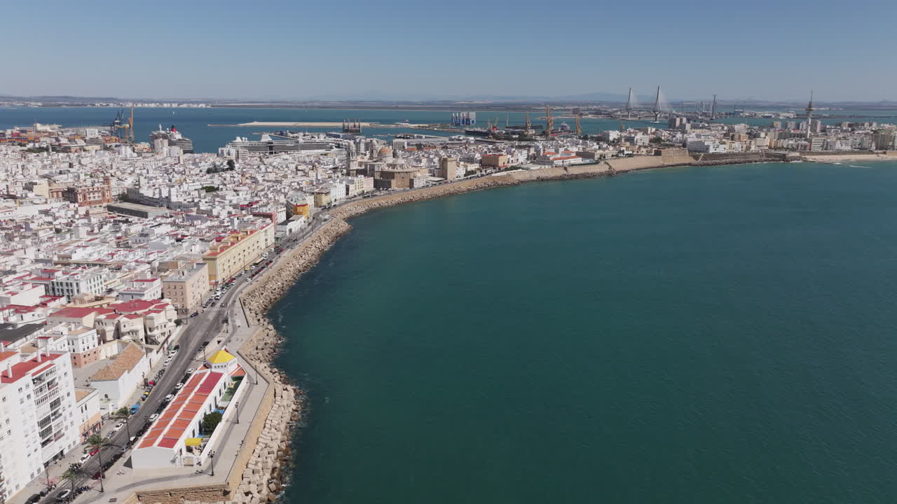 Vista aerea da drone del paesaggio urbano di Cadice, in Spagna, Andalusia, Europa, in una luminosa giornata di sole, rivolta verso la spiaggia de La Caleta e lungo il lungomare della città