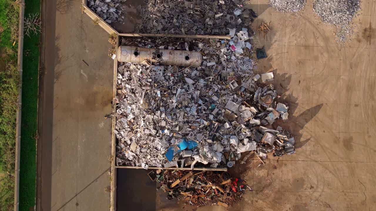 Prospettiva drone di un trafficato sito di riciclo di metalli con imponenti pile di rottami
