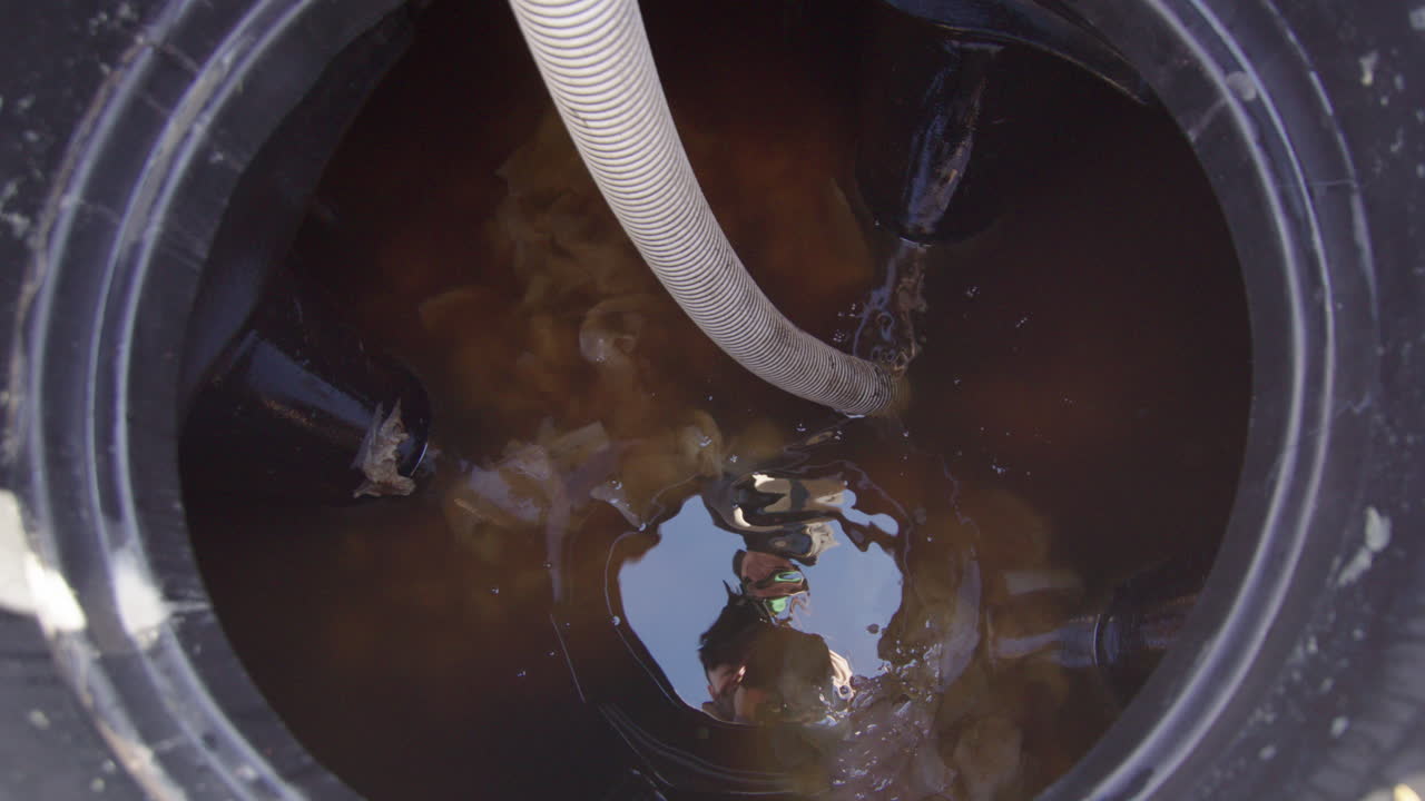 Top view of a suction pipe emptying a closed septic sewage tank