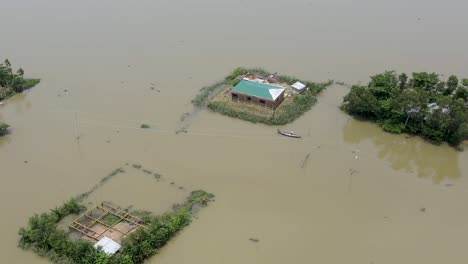 aerial view over boat leaving flood affected submerged village home in bangladesh community