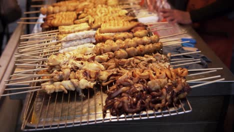 a bangkok marketplace featuring traditional thai skewer dishes on the grill in a close-up view