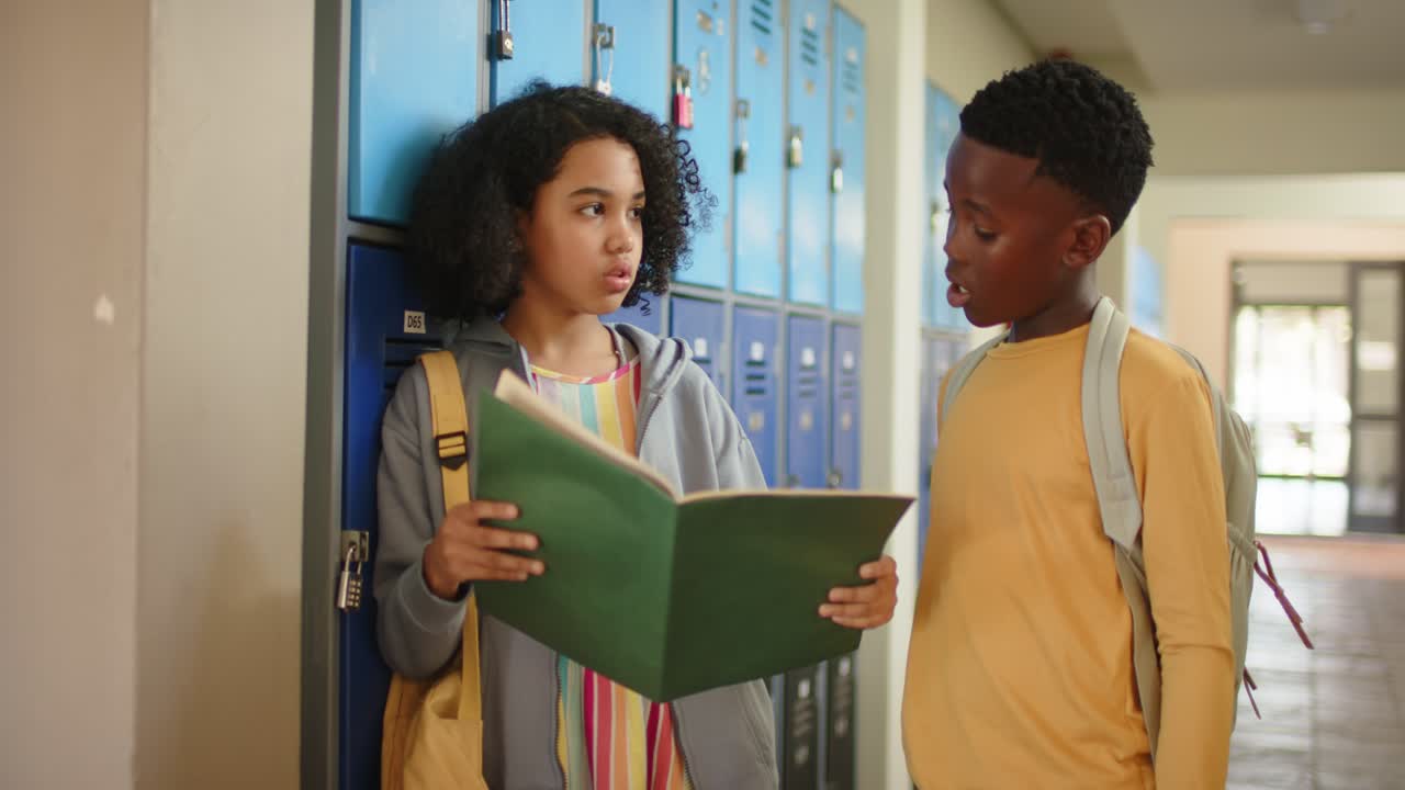 African American teens girl holding binder leaning by lockers at school, boy coming checking notes