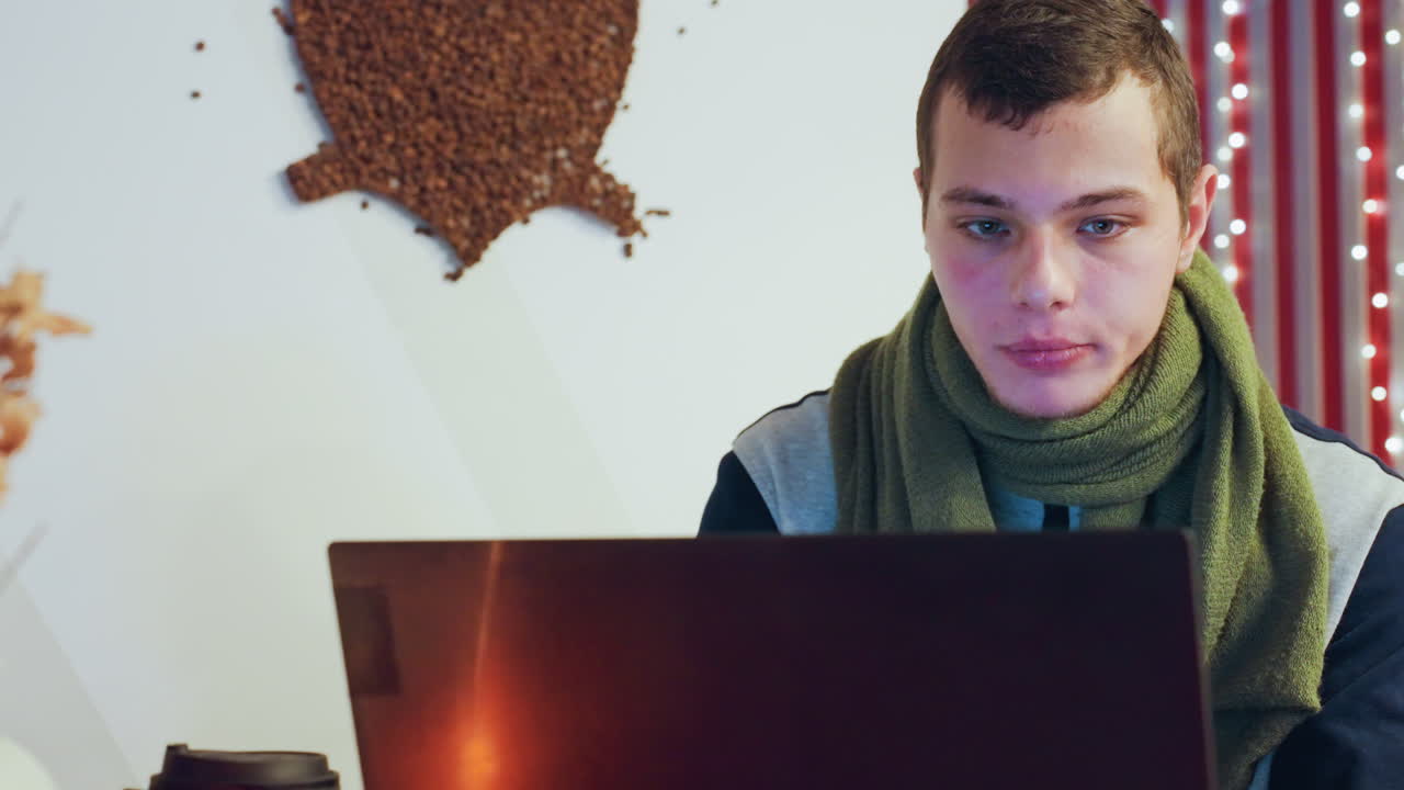 Caucasian man focused on laptop screen, evening glow red striped curtain backdrop with string lights, soft monitor illumination, concentrated expression, remote coding session, quiet study
