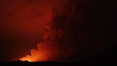 large cloud of smoke rising from volcanic eruption with orange glow from lava