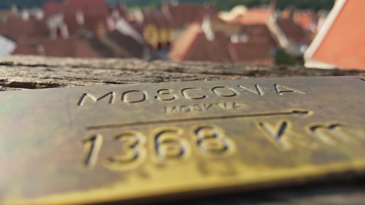 Primo piano di una placca in ottone che indica la distanza da Mosca, Russia, dalla Torre dell'Orologio di Sighișoara, Romania