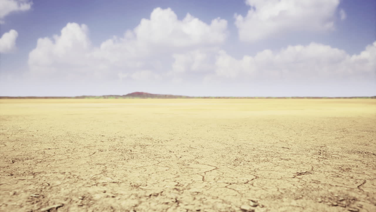 Expansive dry landscape under a blue sky with fluffy clouds at noon
