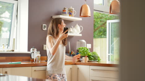 woman in pajamas recording a video in the kitchen