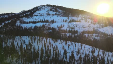 The-sun-rises-over-a-pine-forest-in-the-mountains-of-Tahoe-with-snow-on-the-ground