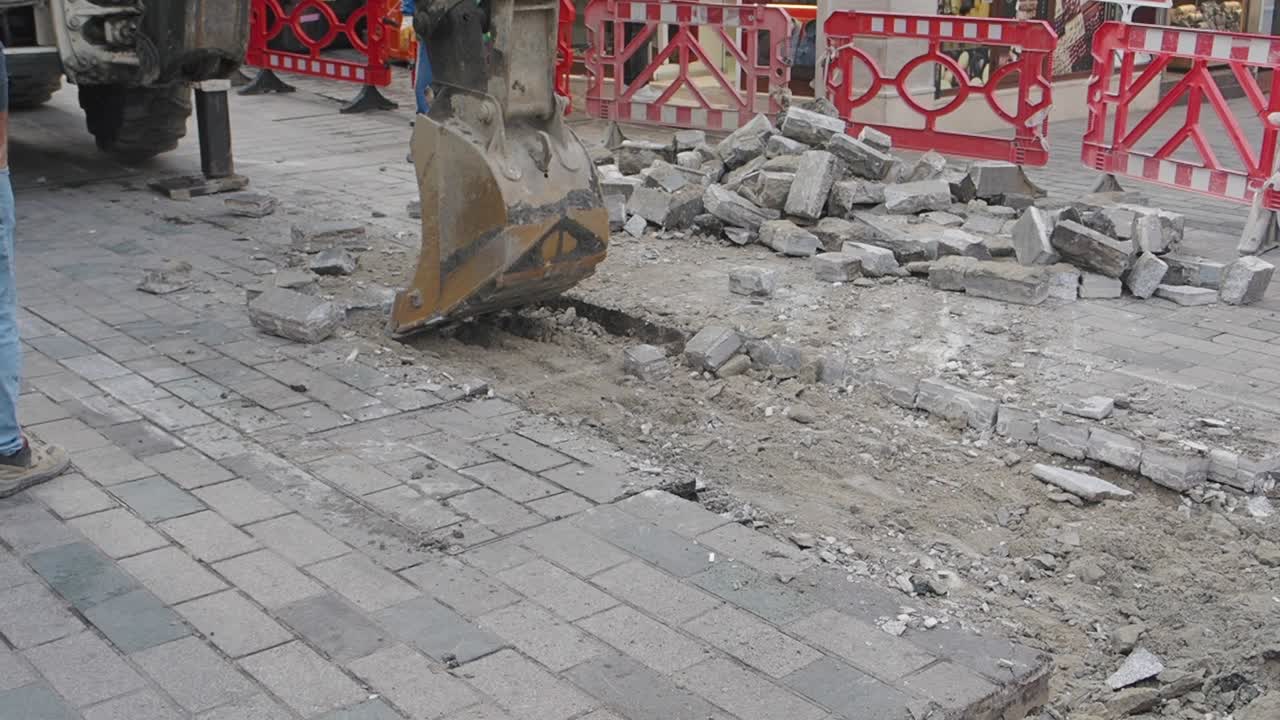 Excavator digging up pavement on a street during construction work
