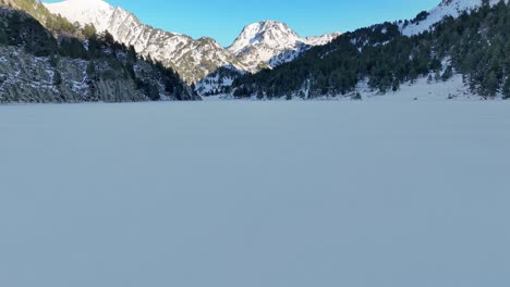 drone footage on a frozen lake, revealing distant mountains in the pyrenees mountains