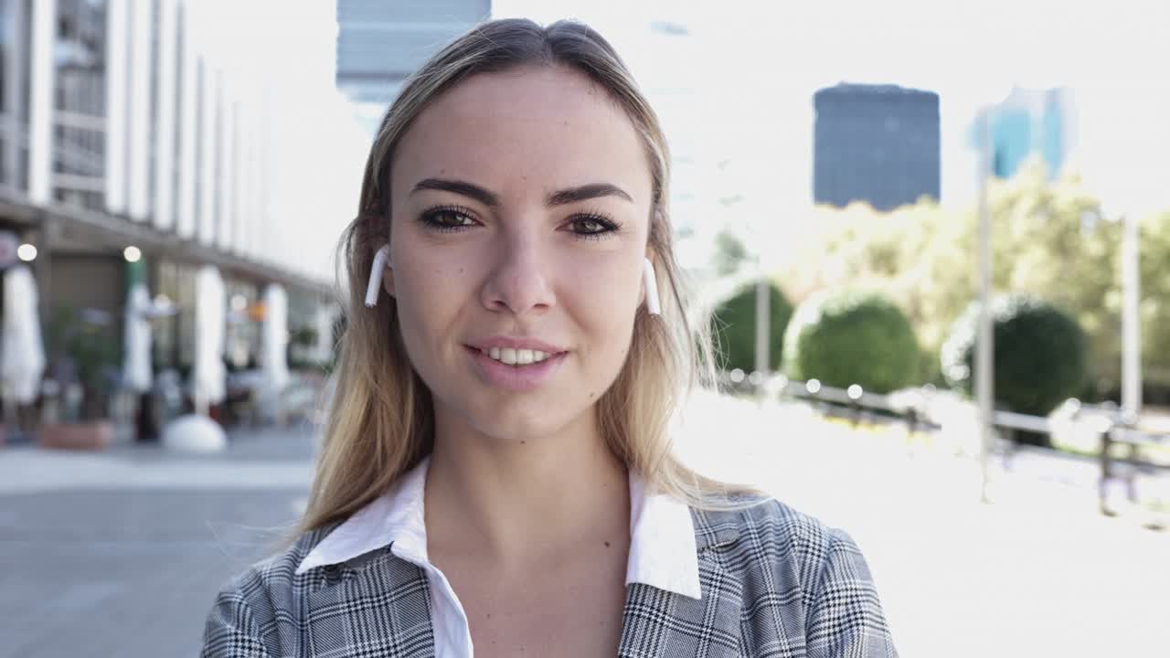 Giovane donna d'affari che sorride alla telecamera all'aperto nel quartiere finanziario.
