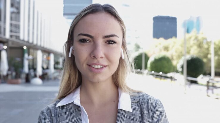 Giovane donna d'affari che sorride alla telecamera all'aperto nel quartiere finanziario.