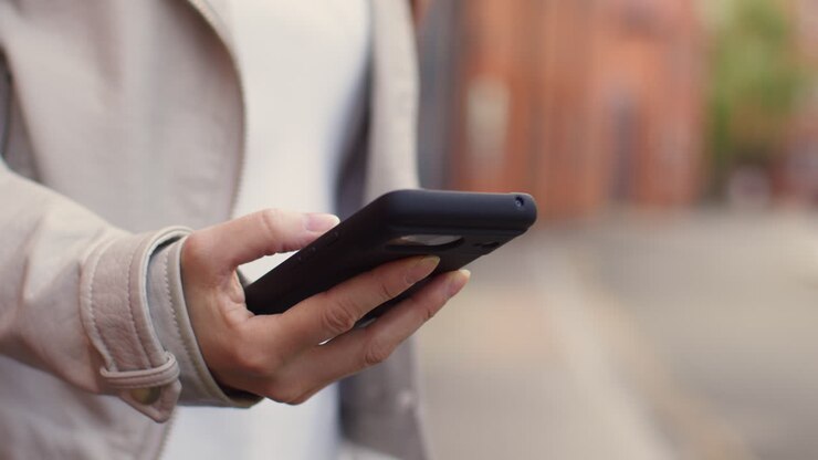 Close Up Shot Of Woman Outdoors On City Street Holding Mobile Phone Looking At Messages Social Media Or News 1