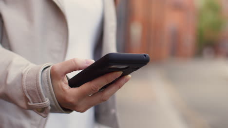 close up shot of woman outdoors on city street holding mobile phone looking at messages social media or news 1