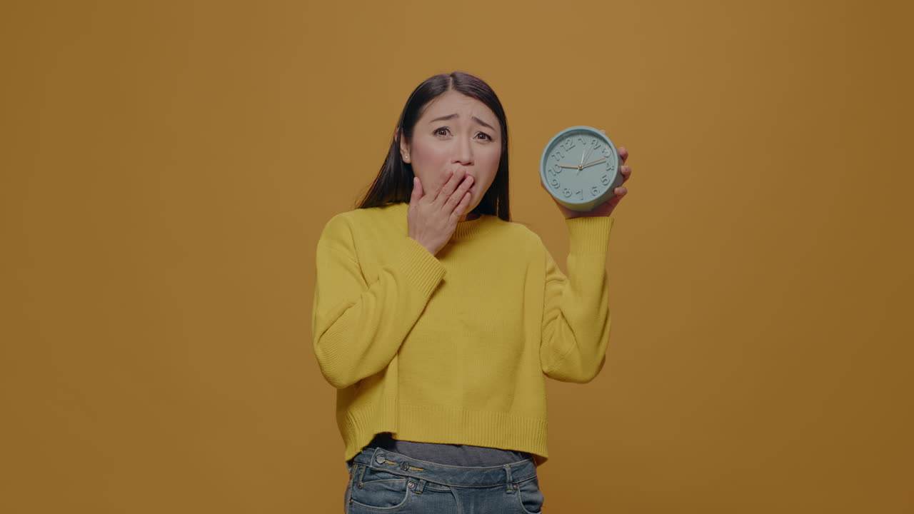 Asian woman with anxiety checking time on clock in studio