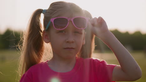 una niña molesta se quita las gafas de sol para mostrar su ojo herido.