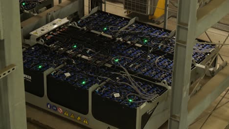 view of rows of battery pack modules laid out and connected to each other with wires and green led status light