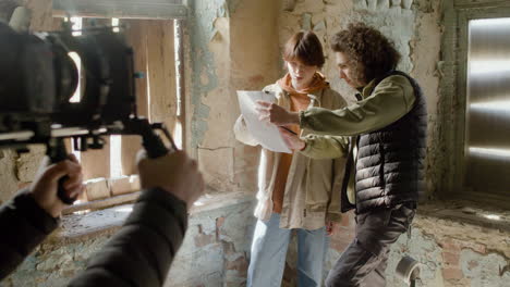 coworkers reading a script in a ruined building while they are being recorded by a cameraman 2