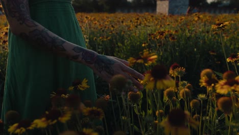 woman in a green dress among flowers at sunset