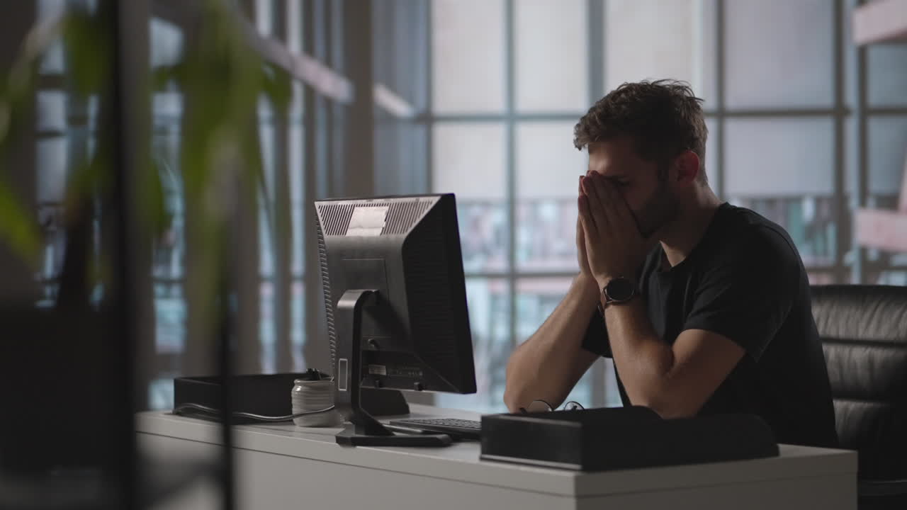 A serious man sits at a computer in the office and thinks. Analyzes solves a crisis problem. A difficult stage in business. Thoughtful businessman