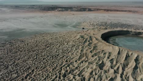 Aerial-Circle-Dolly-Around-Mud-Volcano-With-Black-4x4-Parked-On-Side-In-Balochistan