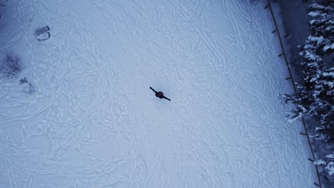 unrecognizable person spinning around on snowy winter forest glade