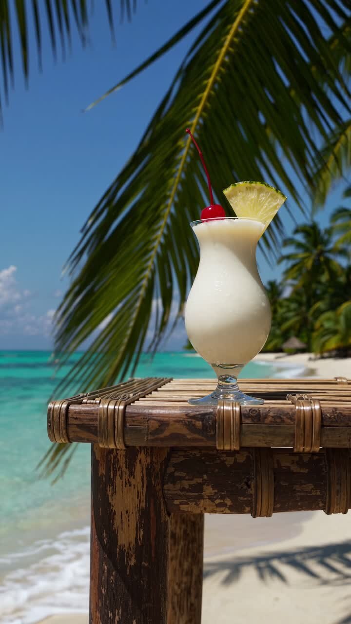 Tropical paradise video concept with a low-angle shot of a pina colada on a rustic table, framed