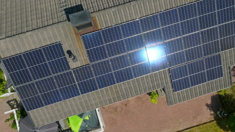 aerial: sunlight mirroring from the photovoltaic surface on a modern house roof