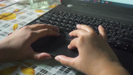 a close up view of a female hand typing on the laptop at home, slow-mo