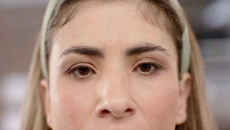 portrait close up of eyes of biracial creative businesswoman smiling in office, in slow motion