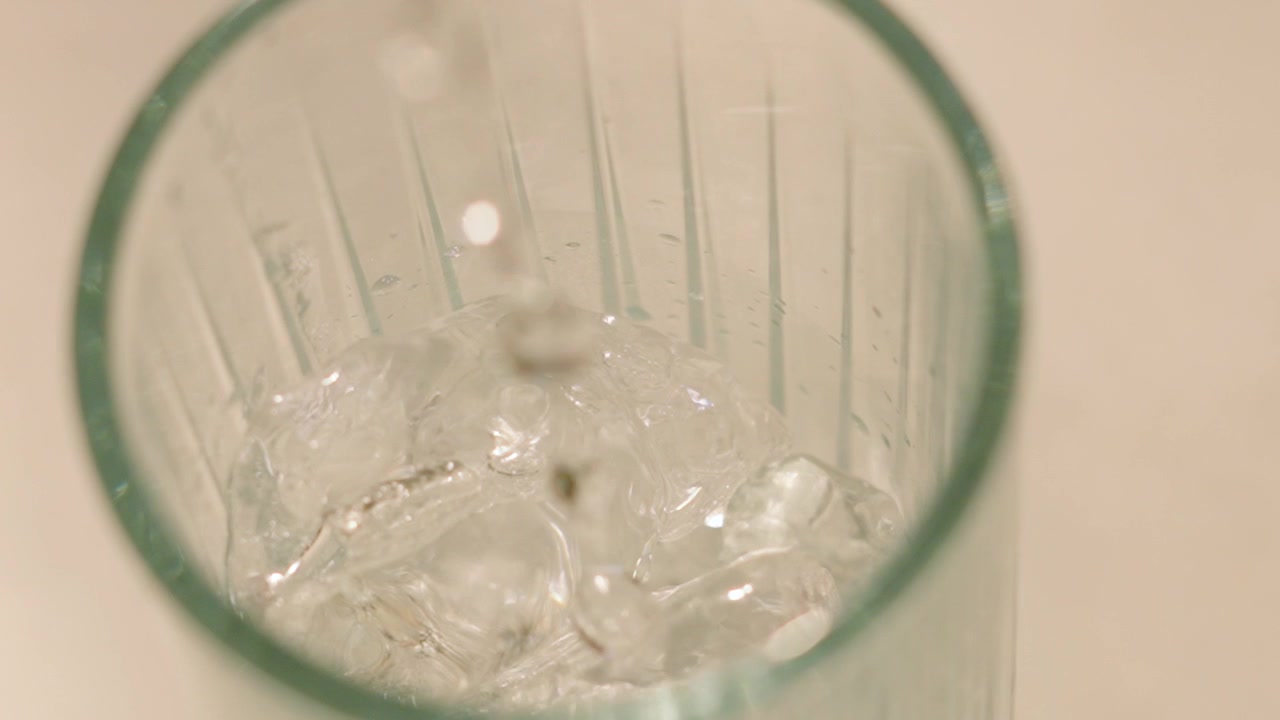 Acqua tonica versata in un bicchiere alto con gin e ghiaccio al rallentatore. Bevanda alcolica fresca e rinfrescante. 4K