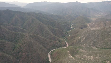 Sinuoso-Camino-Serpenteante-Se-Abre-Paso-A-Través-De-Terrenos-Accidentados-De-Montañas,aéreo