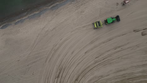 industrial tractor with drawn machinery driving on sand