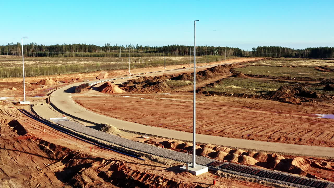 Railway construction progresses through an industrial park under blue sky, aerial view
