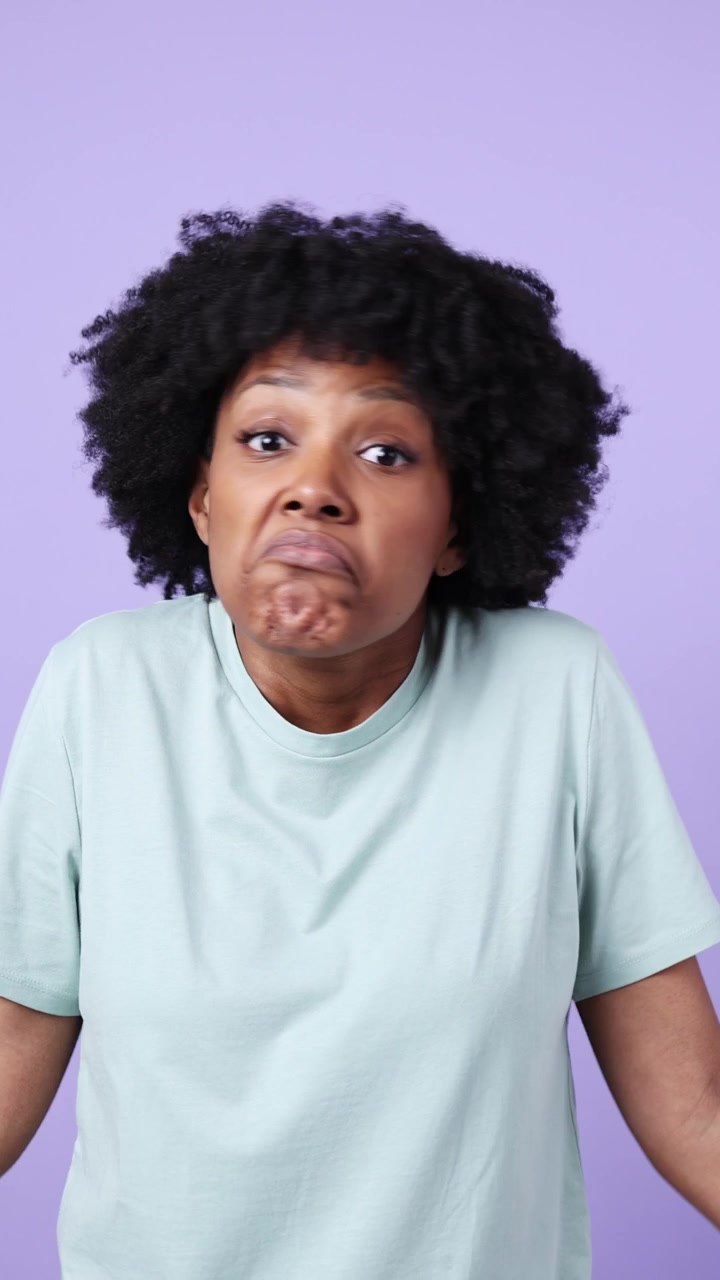 Giovane donna afroamericana che alza le spalle con espressione confusa