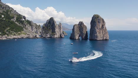 boats by faraglioni famous rock landmarks off capri island, italy - aerial